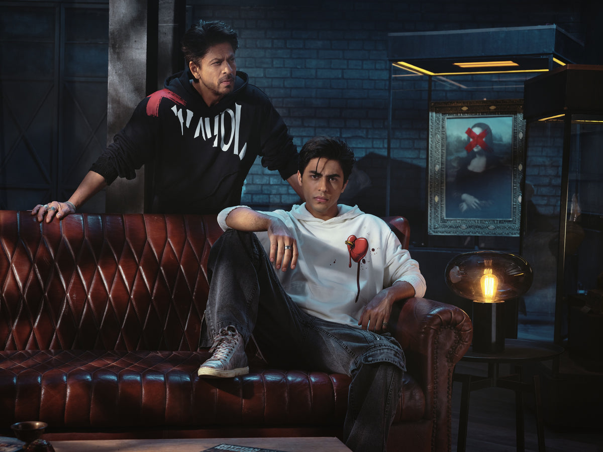 Two members of the D’YAVOL world seated on a leather sofa